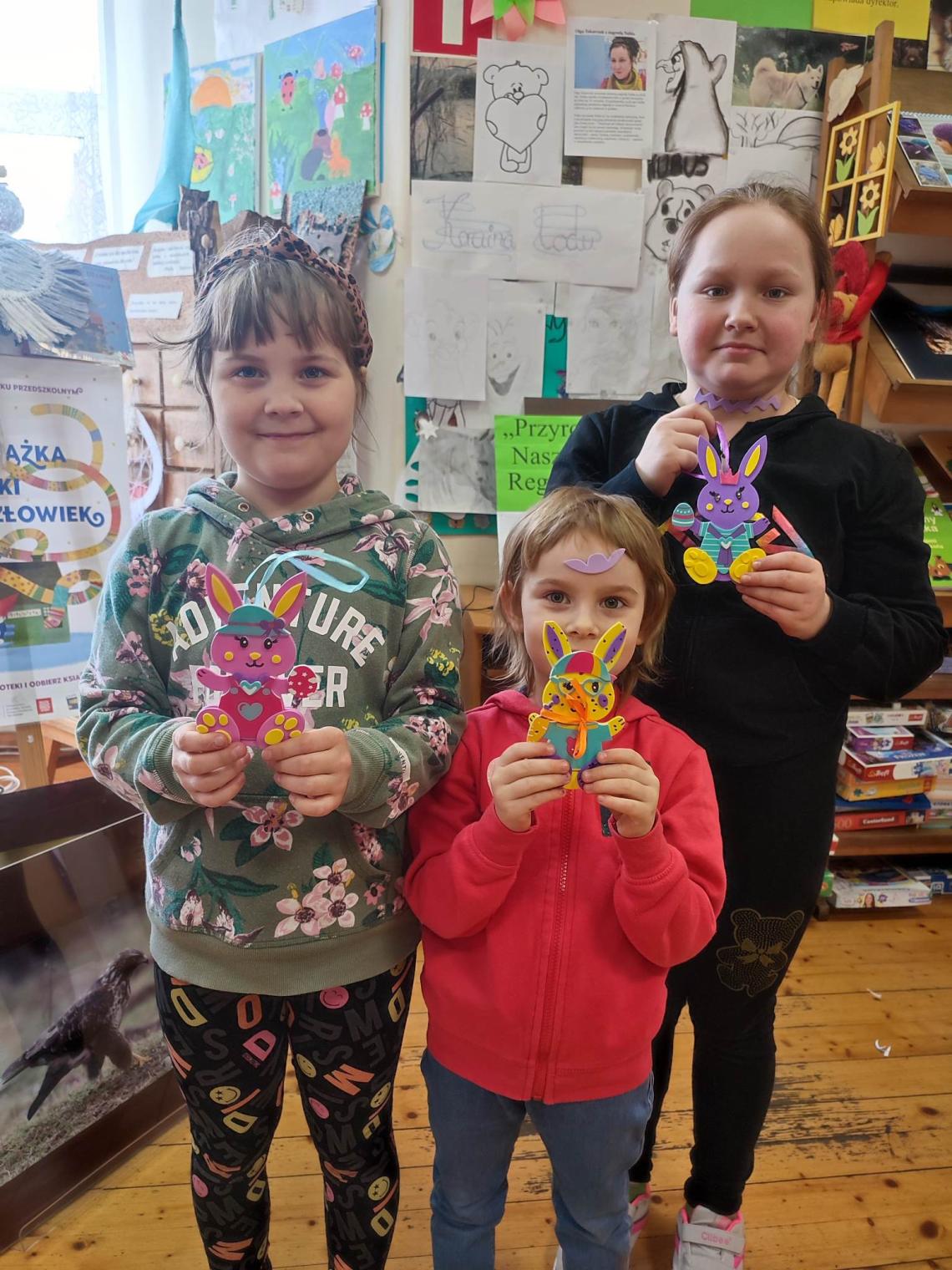 Uczestnicy warsztatów wielkanocnych z wykonanymi ozdobami kolorowymi króliczkami w filii w Podwilczu